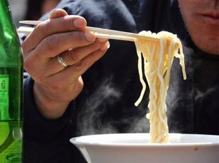 A Chinese man eats noodles with disposable chopsticks at a restaurant in Beijing